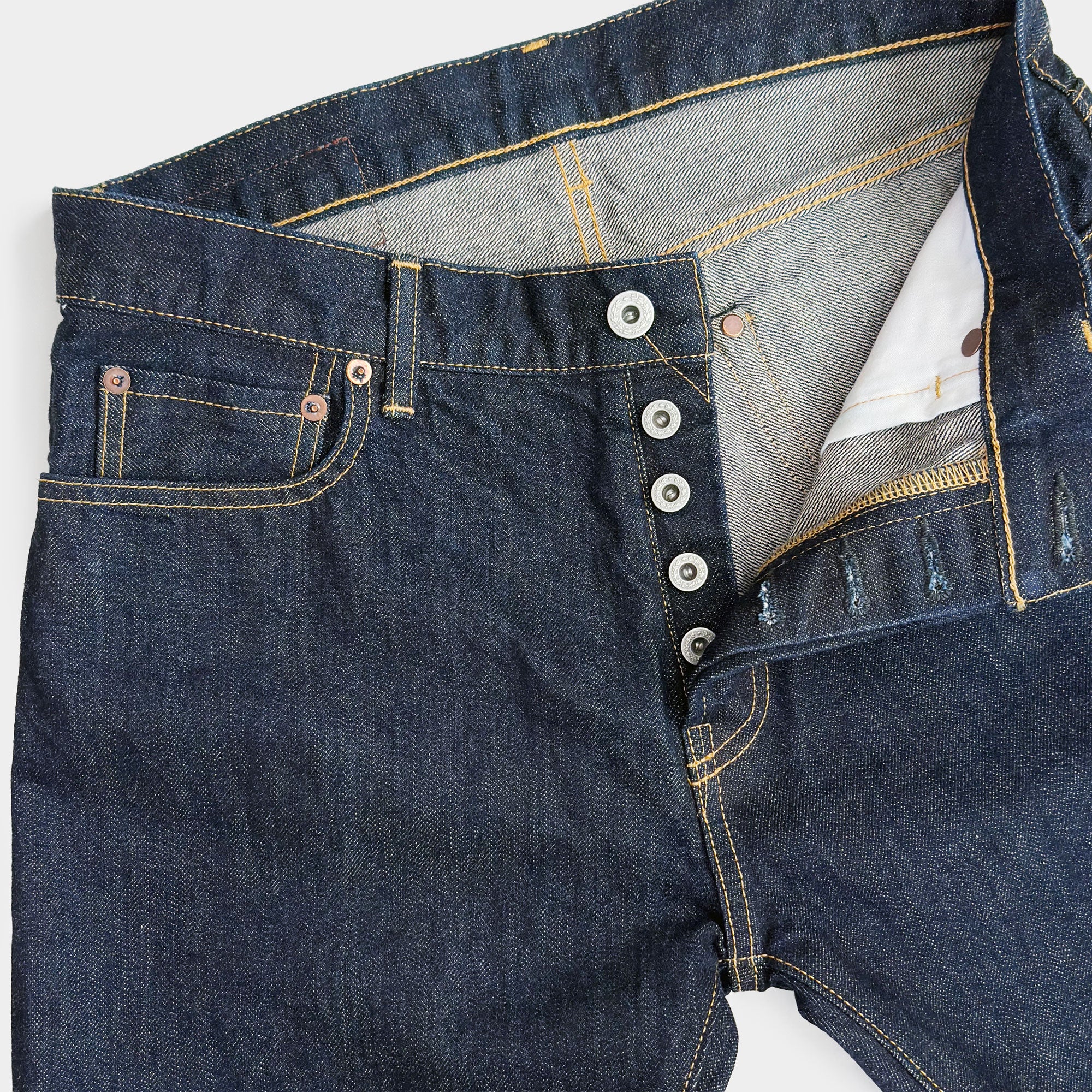 Closeup of HFD-04W Japanese selvedge denim once washed slim fit straight leg jeans showing the button fly, waistband, rivets, and front pockets.