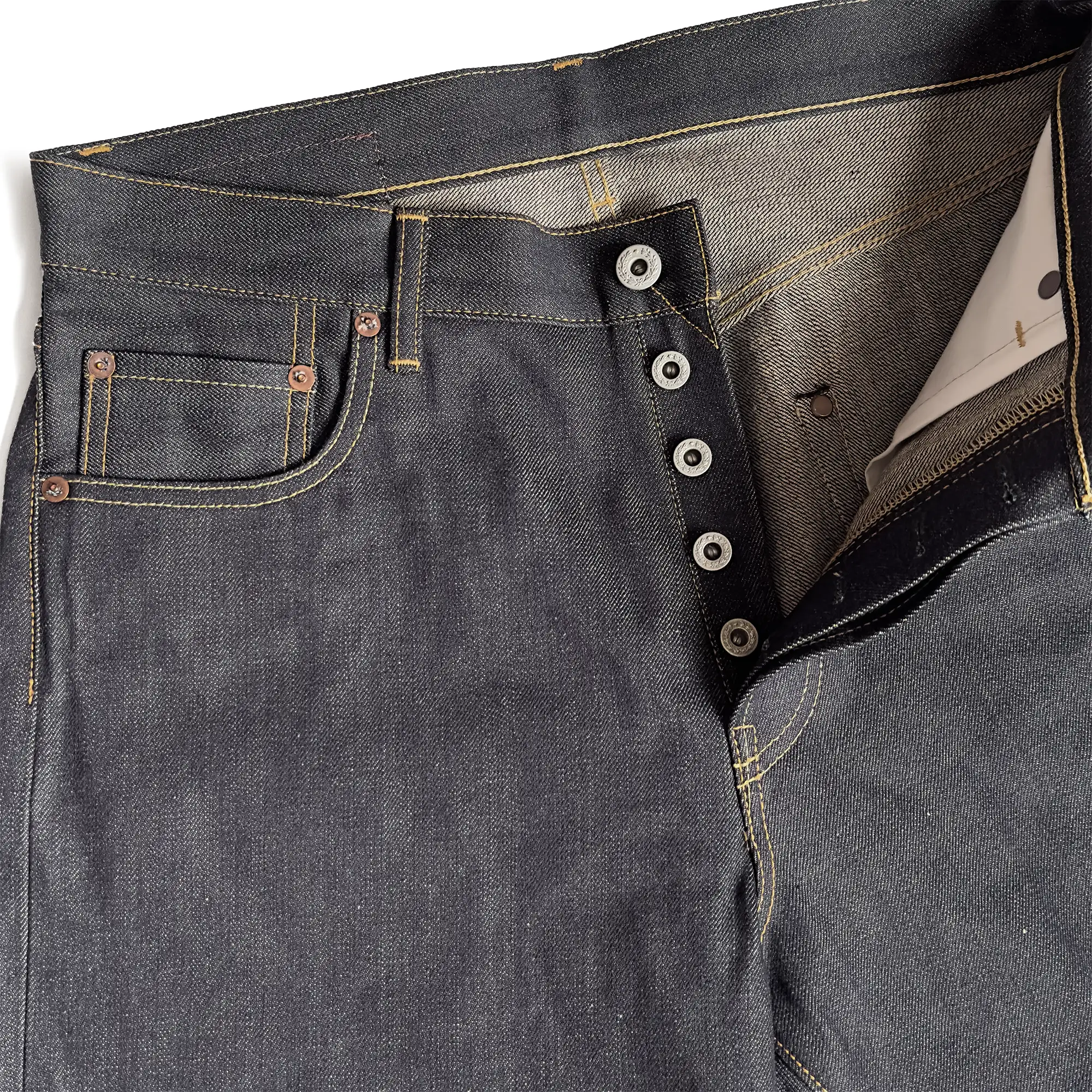 Closeup of HFD-01 Japanese selvedge denim relaxed fit wide leg jeans showing the button fly, waistband, rivets, and front pockets.