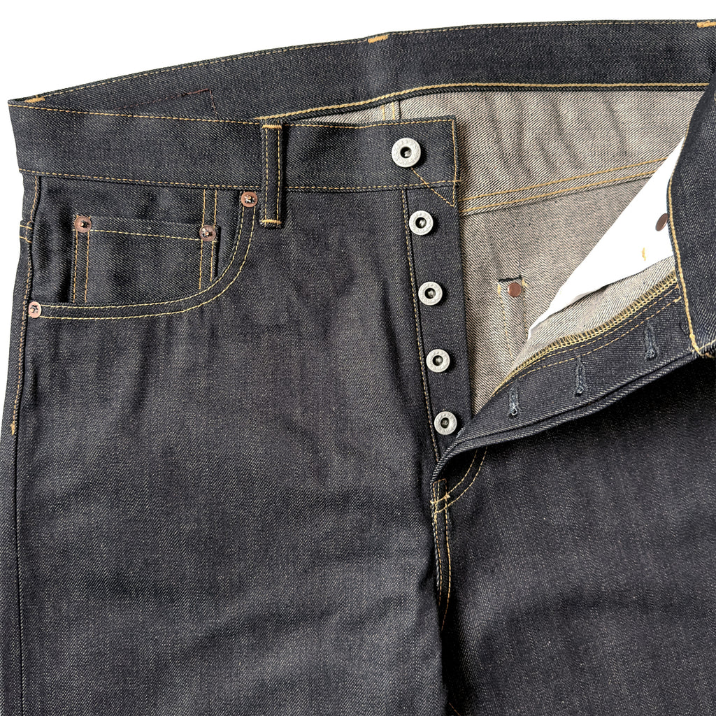 Closeup of HFD02 Japanese selvedge denim relaxed fit tight tapered leg jeans showing the button fly, waistband, rivets, and front pockets.
