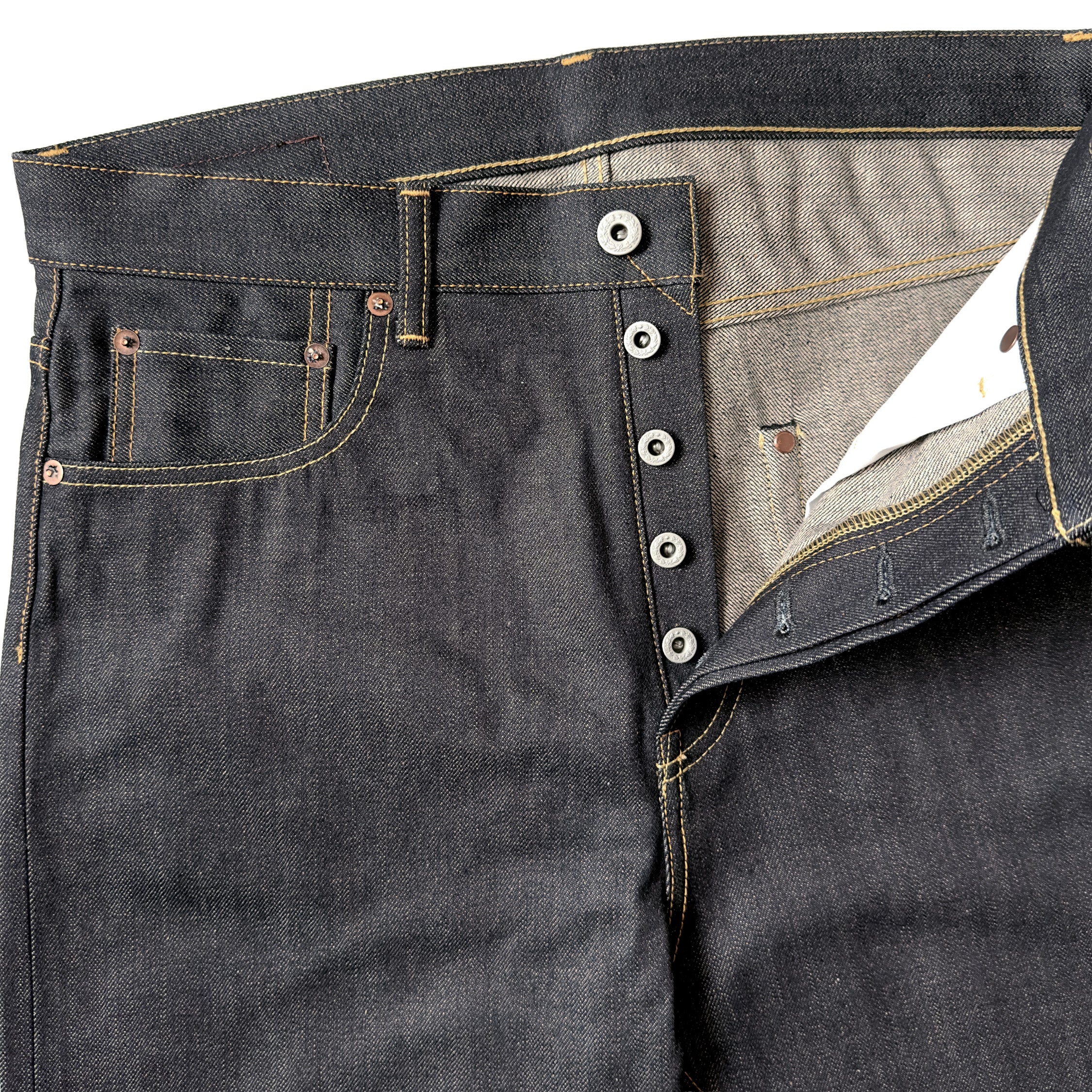 Closeup of HFD02 Japanese selvedge denim relaxed fit tight tapered leg jeans showing the button fly, waistband, rivets, and front pockets.