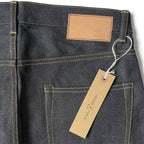 Closeup of the HFD02 jacron paper patch and kraft paper hangtag with logo on Japanese selvedge denim relaxed fit tight tapered leg jeans.