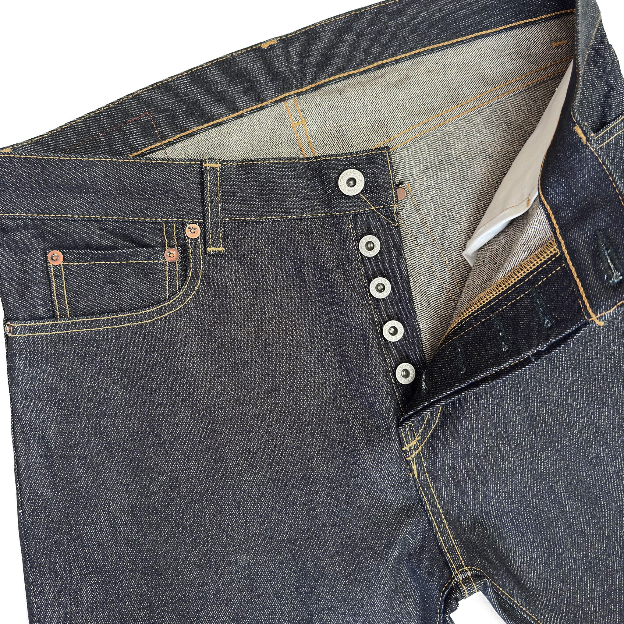 Closeup of HFD04 Japanese selvedge denim slim fit straight leg jeans showing the button fly, waistband, rivets, and front pockets.