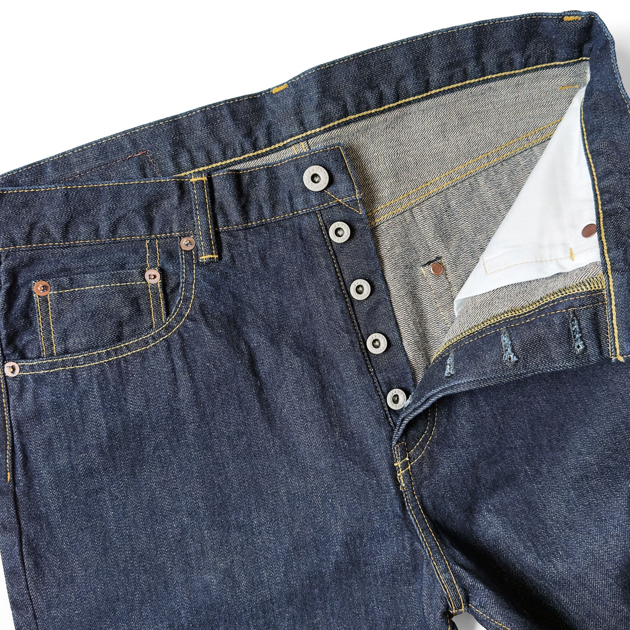 Closeup of HFD-02 Japanese selvedge denim once washed  relaxed fit tight tapered leg jeans showing the button fly, waistband, rivets, and front pockets.