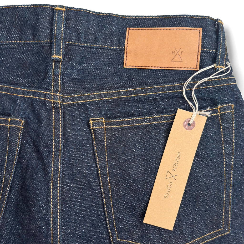 Closeup of the HFD-04W jacron paper patch and kraft paper hangtag with logo on Japanese selvedge denim once washed slim fit straight leg jeans.